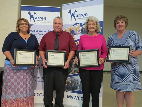 four people holding awards